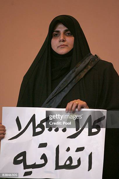 Maha al-Dori, a lawmaker loyal to anti-American Shiite cleric Muqtada al-Sadr, holds banners that say "No, no to the agreement" after Iraqi...