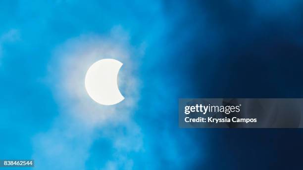 partial solar eclipse observed in costa rica, cloudy sky - zonsverduistering stockfoto's en -beelden