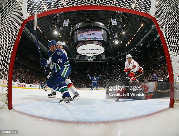 Darcy Hordichuk of the Vancouver Canucks scores his first goal as a Canuck on Miikka Kiprusoff of the Calgary Flames while teammate Jannik Hansen of...