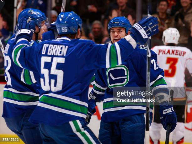 Darcy Hordichuk of the Vancouver Canucks is congratulated by teammates after scoring while Dion Phaneuf of the Calgary Flames skates away dejected...