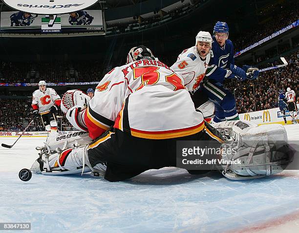 Mark Giordano of the Calgary Flames and teammate Curtis Glencross watch as the puck goes through the crease of Miikka Kiprusoff of the Flames with...