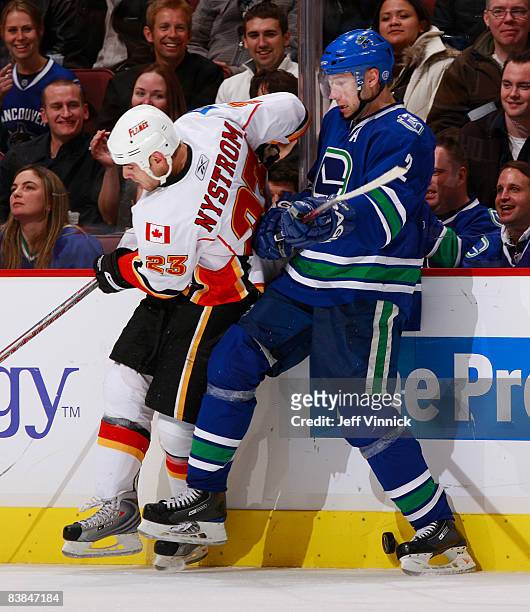 Mattias Ohlund of the Vancouver Canucks shields the puck along the boards from Eric Nystrom of the Calgary Flames during their game against the...