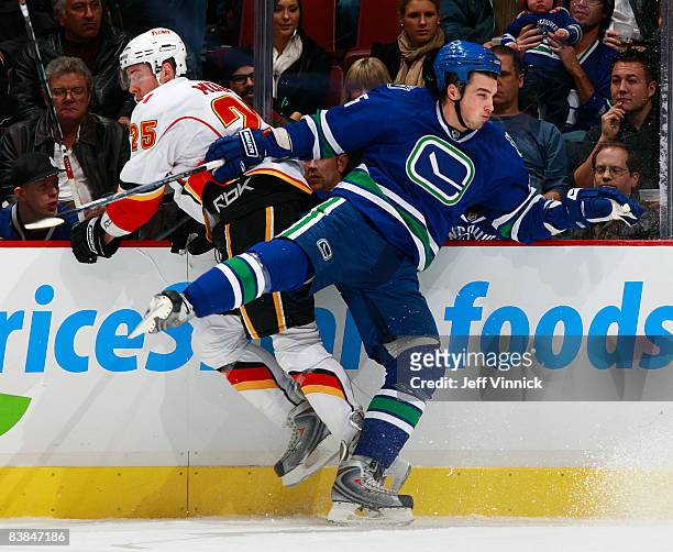 Shane O'Brien of the Vancouver Canucks checks David Moss of the Calgary Flames hard into the boards during their game against the Calgary Flames at...