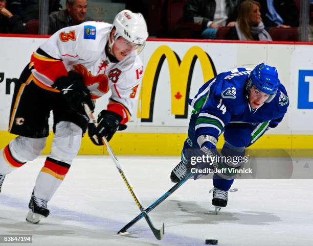 Alexandre Burrows of the Vancouver Canucks and Dion Phaneuf of the Calgary Flames race after the puck during their game against the Calgary Flames at...