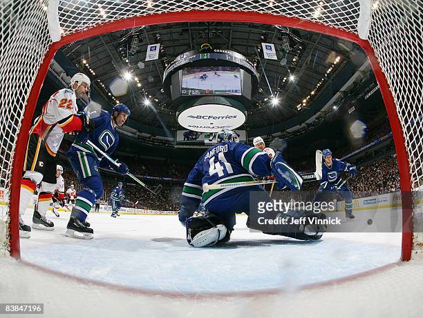 Willie Mitchell of the Vancouver Canucks and teammate Kevin Bieksa protect the crease after Curtis Sanford makes a pad save with Daymond Langkow of...