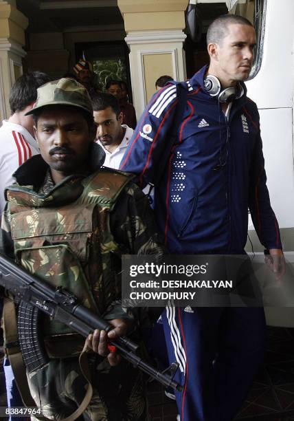 England cricket captain Kevin Pietersen walks to board a bus while Indian security personnel stand alert outside a hotel housing the England cricket...