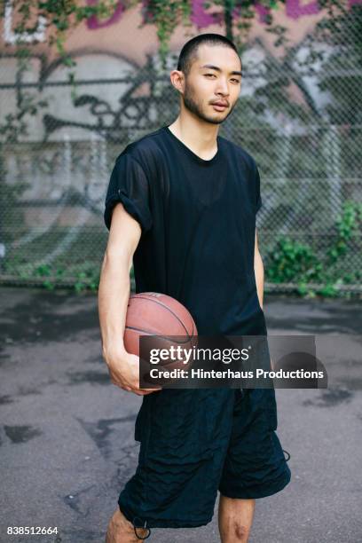 stylish young basketball player holding ball - young man holding basketball stockfoto's en -beelden