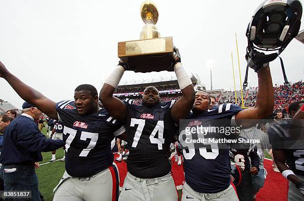 Michael Oher of the Ole Miss Rebels hoists the Golden Egg with teammates after a victory over the Mississippi State Bulldogs during their game at...