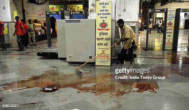 Railway worker clears the CST station floor where the terrorist attack took place on November 26, 2008 in Mumbai, India. Following terrorist attacks...