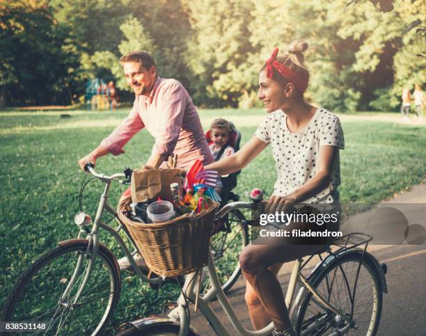 young family riding bicycles in the park - basket sport stock pictures, royalty-free photos & images