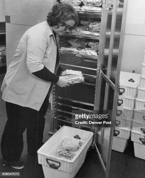 Betty Bell, HCS supervisor, removes wrapped, labeled meals from warming oven and packs them 12-deep into insulated hamper for home delivery. Credit:...