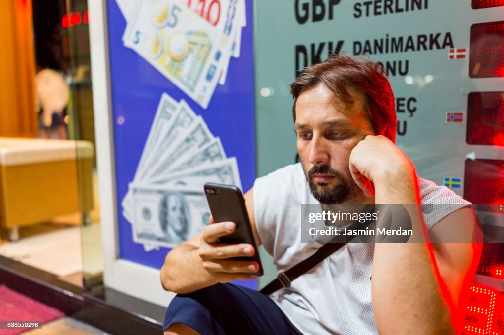 Man in front of bank office using his phone