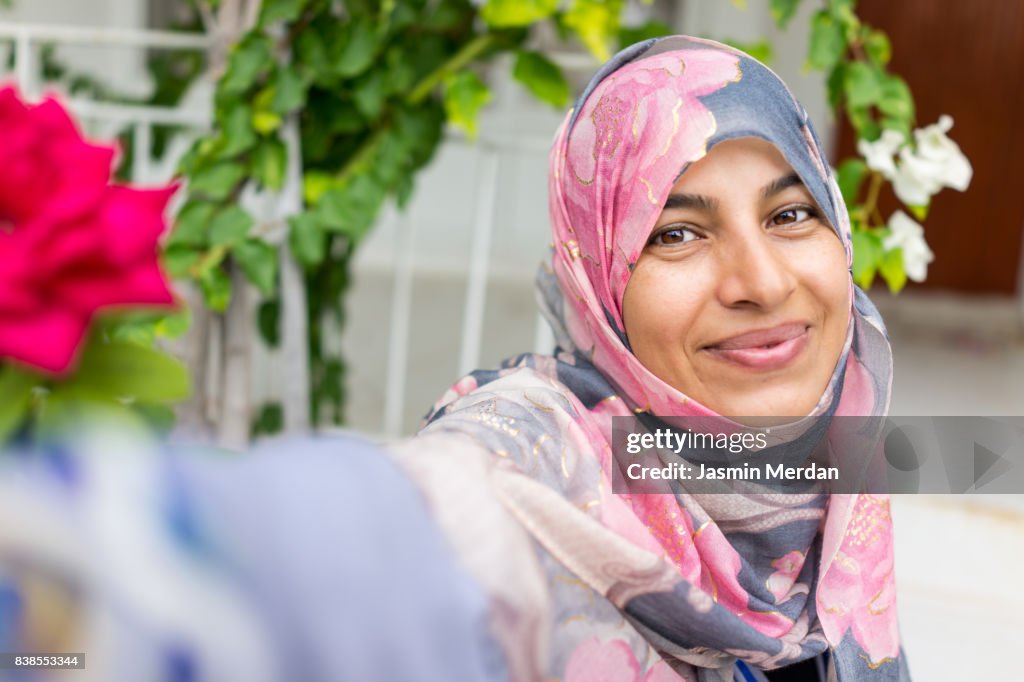 Muslim woman sitting in backyard making selfie with phone