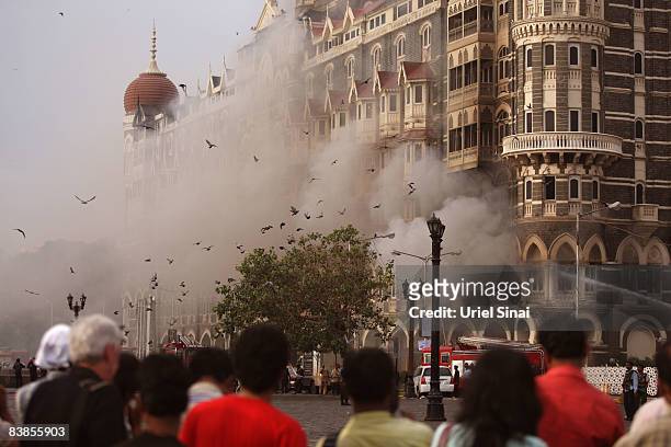 Locals look at a fire as it burns at Taj Mahal Palace & Tower Hotel following an armed siege on November 29, 2008 in Mumbai, India. Indian officials...
