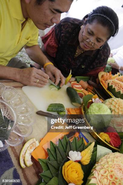Woman teaching a man how to carve fruit at the Asian Culture Festival at Fruit and Spice Park.