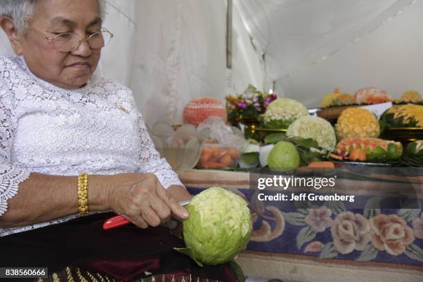 Senior woman demonstrating how to carve fruit at the Asian Culture Festival at Fruit and Spice Park.