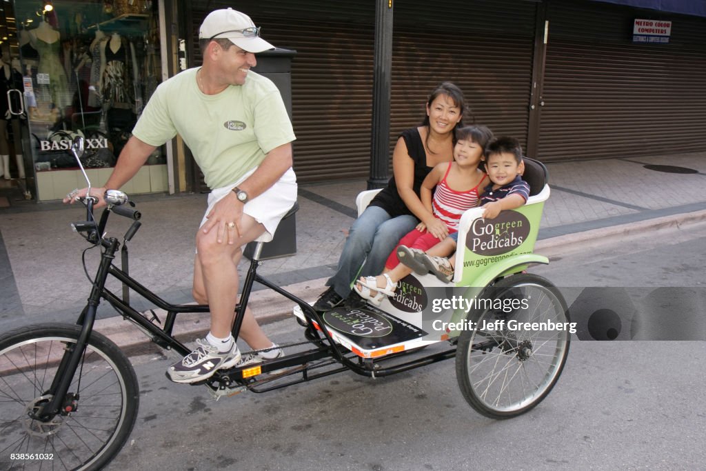 A family riding a Pedi-cab on Flagler Street.