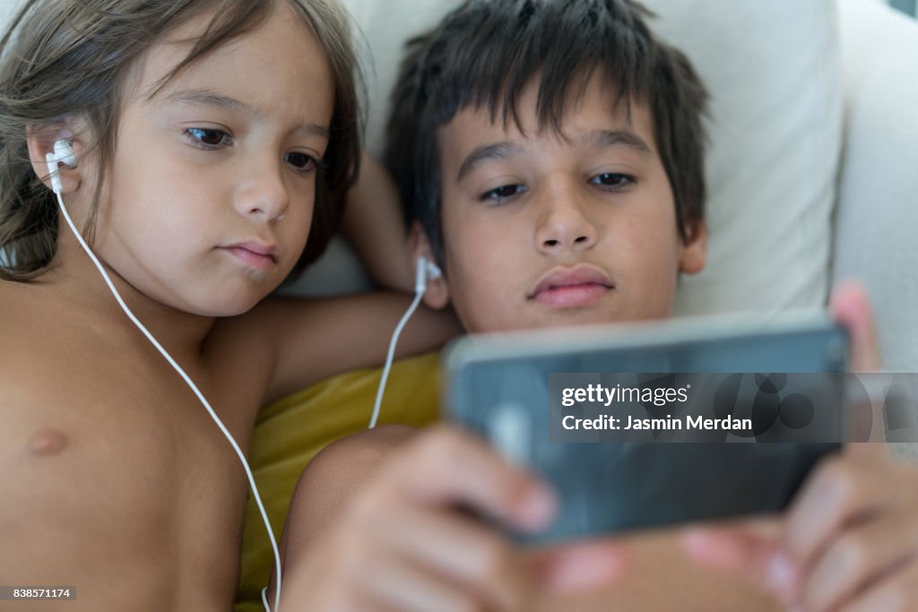 Two boys using mobile phone together indoors