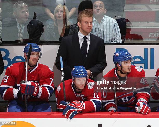 Injured player Mike Komisarek of the Montreal Canadiens takes on a role of assistant coach behind the bench for a game against the Buffalo Sabres at...