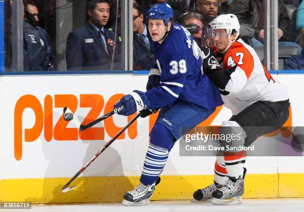 John Mitchell of the Toronto Maple Leafs passes the puck as he is defended by Luca Sbisa of the Philadelphia Flyers during their NHL game at the Air...