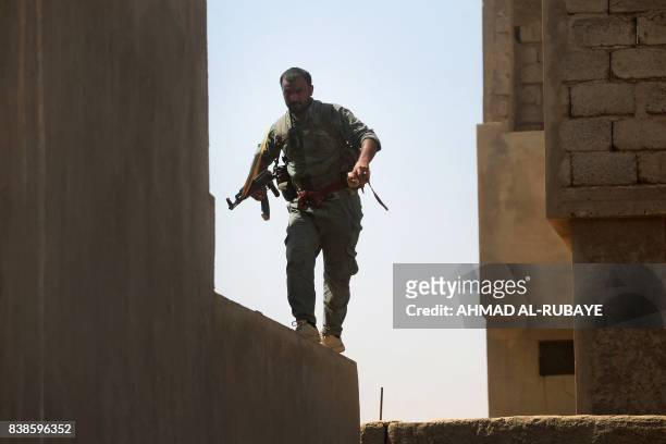 Fighter from the Hashed al-Shaabi , backing the Iraqi forces, takes position as troops advance through Tal Afar's al-Wahda district during an...