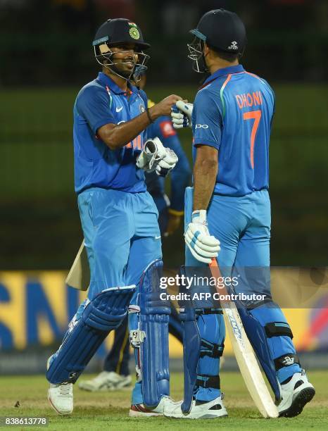 Indian batsman Bhuvneshwar Kumar celebrates with teammate Mahandra Singh Dhoni after victory in the second one day international cricket match...