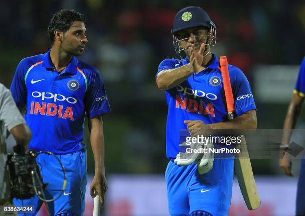 Indian cricketers M S Dhoni and Bhuvneshwar Kumar walk back after securing a 3 wicket victory during the 2nd One Day International cricket match...