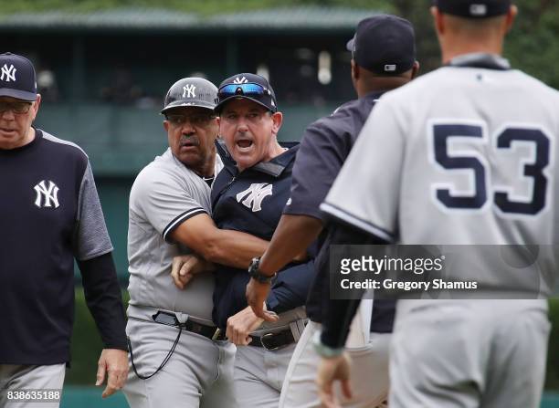 Acting manager Rob Thomson of the New York Yankees is held back by first base coach Tony Pena after Dellin Betances was ejected from the game after...