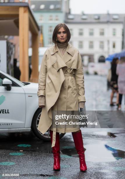 Darja Barannik wearing a trench coat, red boots, green bag outside Bik Bok Runway Award on August 24, 2017 in Oslo, Norway.