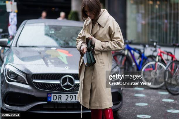 Darja Barannik wearing a trench coat, red boots, green bag outside Bik Bok Runway Award on August 24, 2017 in Oslo, Norway.