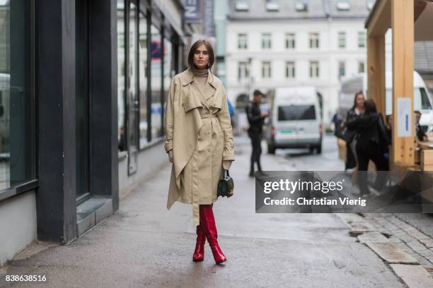 Darja Barannik wearing a trench coat, red boots, green bag outside Bik Bok Runway Award on August 24, 2017 in Oslo, Norway.