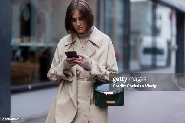 Darja Barannik wearing a trench coat, red boots, green bag outside Bik Bok Runway Award on August 24, 2017 in Oslo, Norway.