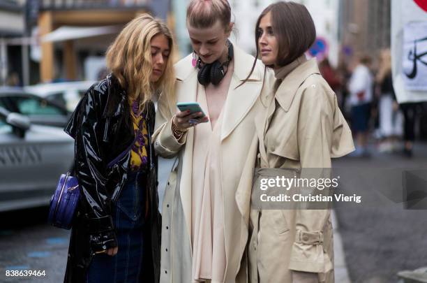 Guests looking at a phone Emili Sindlev wearing a black rain coat, Marianne Theodorsen wearing a trench coat, pastel dress, boots and Balenciaga bag,...