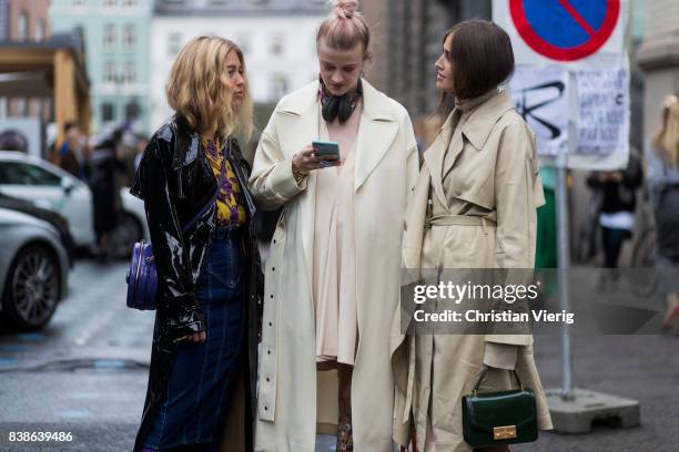 Guests looking at a phone Emili Sindlev wearing a black rain coat, Marianne Theodorsen wearing a trench coat, pastel dress, boots and Balenciaga bag,...