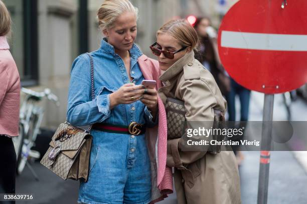 Guests looking at a phone wearing Gucci bag, trench coat, denim dress outside Bik Bok Runway Award on August 24, 2017 in Oslo, Norway.