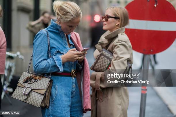 Guests looking at a phone wearing Gucci bag, trench coat, denim dress outside Bik Bok Runway Award on August 24, 2017 in Oslo, Norway.