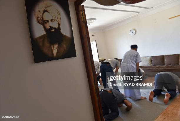 Members of Algeria's small Ahmadi community pray at a house in Tilpasi, west of Algiers, near a photo of Mirza Ghulam Ahmad the founder of the...