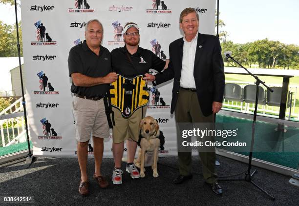 Veteran Adam LeGran, center, with his service dog Molly, pose with Robert Cohen of Stryker, left, and Tim Crosby, right, of K9's for Warriors at the...