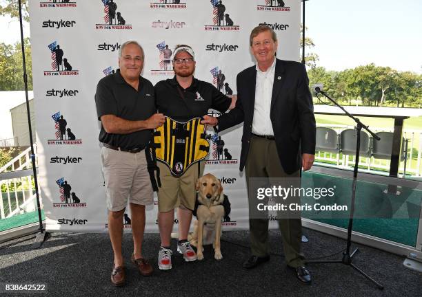Veteran Adam LeGran, center, with his service dog Molly, pose with Robert Cohen of Stryker, left, and Tim Crosby, right, of K9's for Warriors at the...