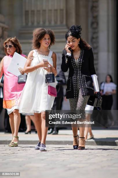 Guest wears a white lace dress, a pink bag ; a guest wears a Chanel black tweed jacket, outside the Chanel show, during Paris Fashion Week - Haute...