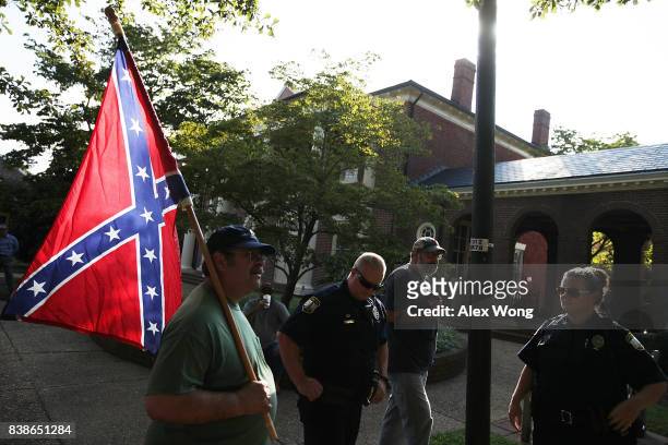 Local resident Gregory Everett carries a Confederate flag to show support for a Confederate soldier statue during a rally by activist groups calling...