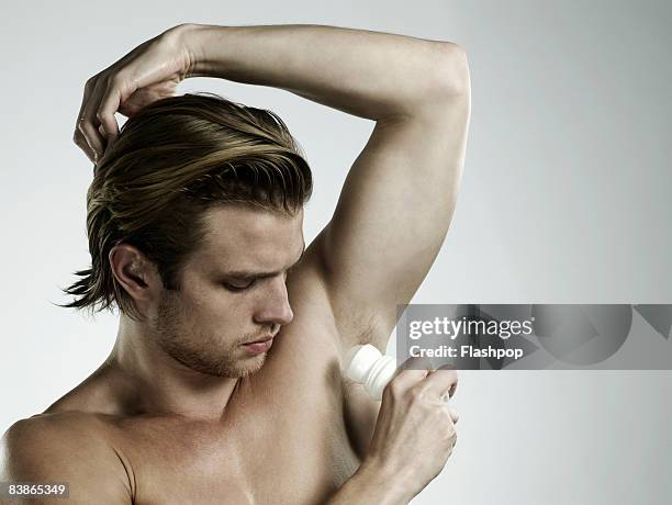 portrait of man applying deodorant - deodorant stock pictures, royalty-free photos & images