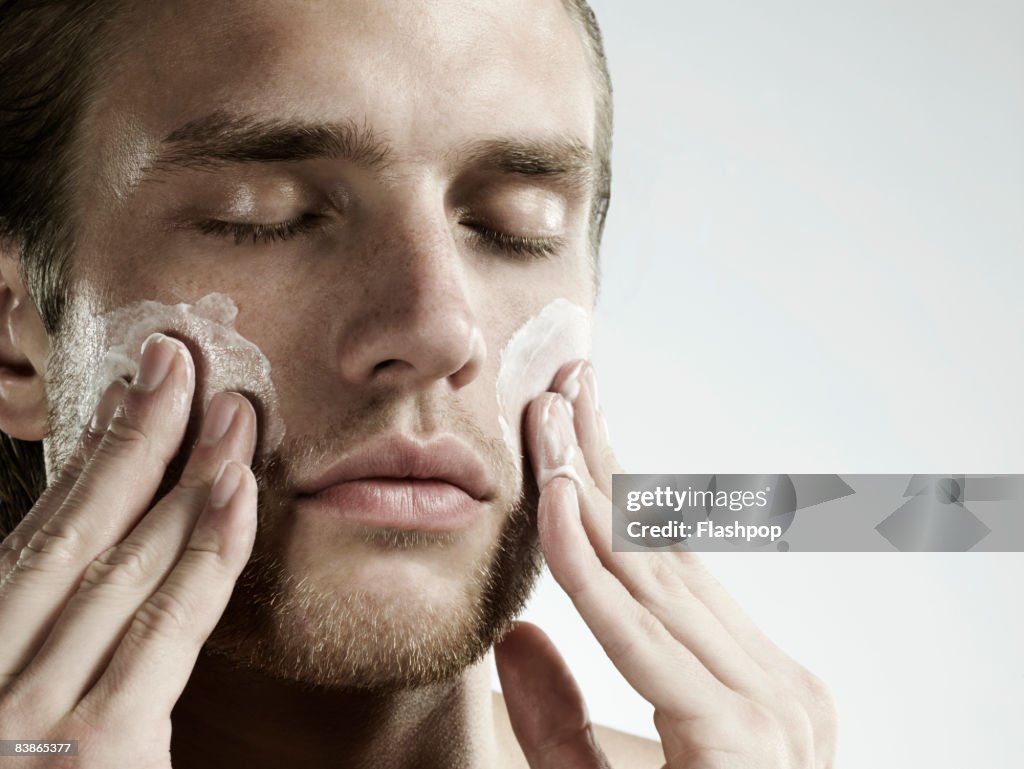 Portrait of man applying moisturizer to face