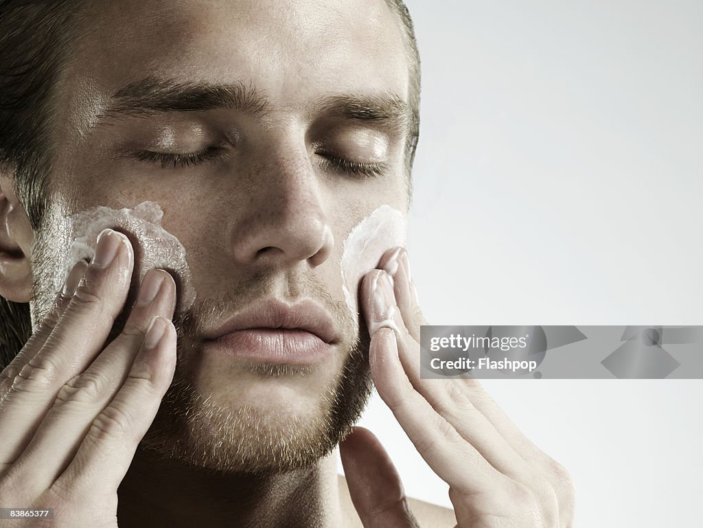 Portrait of man applying moisturizer to face