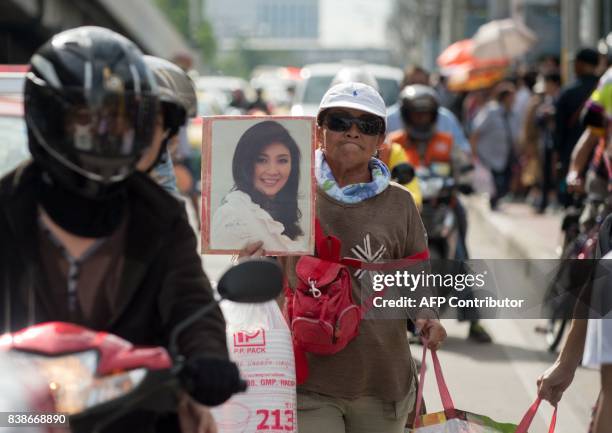 Supporter carries a photo of former Thai Premier Yinluck Shinawatra as they wait for her arrival at the Supreme Court in Bangkok on August 25, 2017....