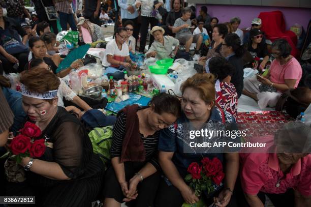 Supporter of former Thai Premier Yinluck Shinawatra cooks while others sit on a sidewalk as they wait for her arrival at the Supreme Court in Bangkok...