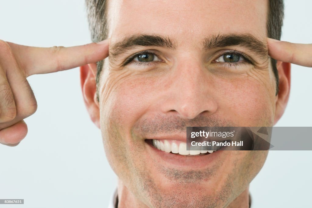 Man putting fingers to temples, smiling