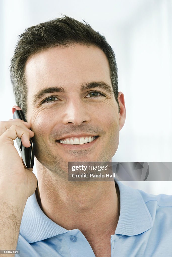 Man using mobile phone, smiling, close-up