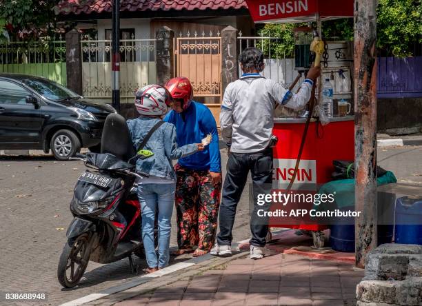 Motorists purchase gasoline from a portable gas station in Jakarta, on August 25, 2017. The economy grew a slower-than-expected 5.01 percent in the...