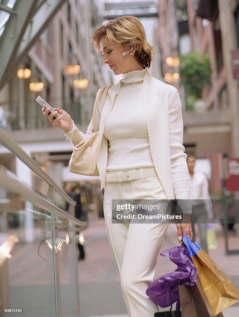 Woman using cellular phone while shopping